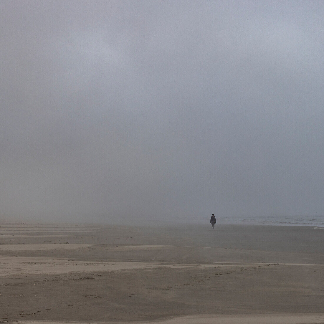 Misty figure walks along beach 