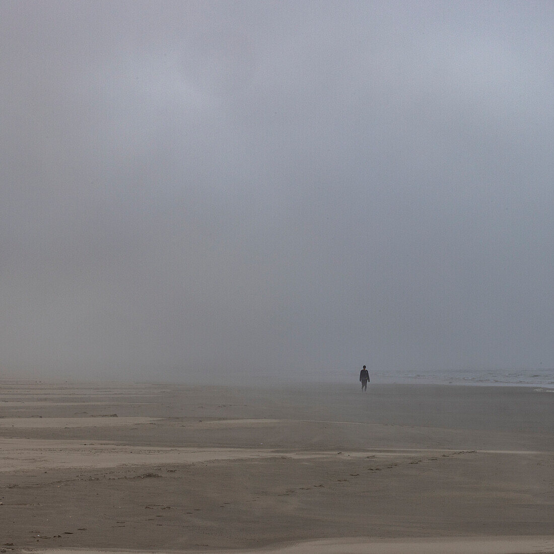 Neblige Gestalt geht am Strand entlang