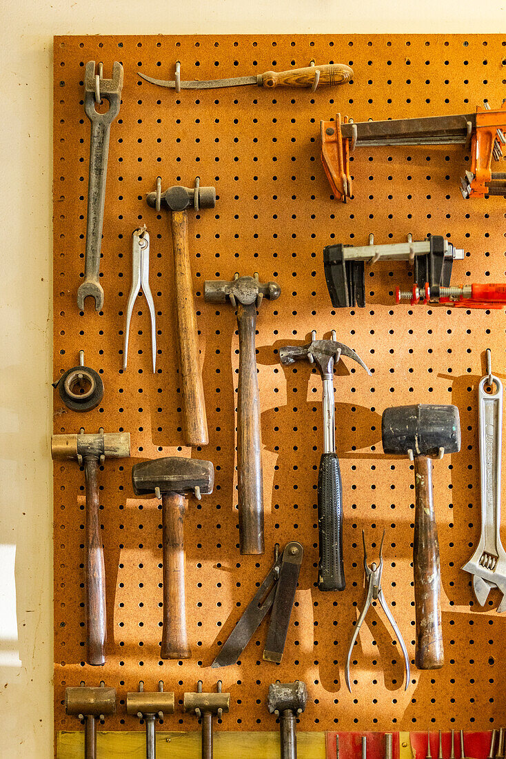 Tools on pegboard hooks on wall of wood and metal shop