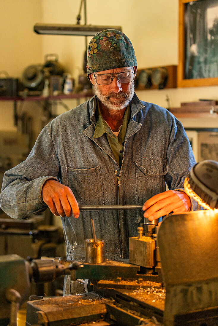 Senior artisan wood and metal craftsman works with tools in workshop