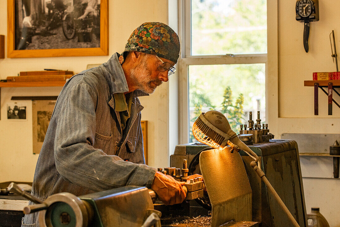 Senior artisan wood and metal craftsman works with tools in workshop