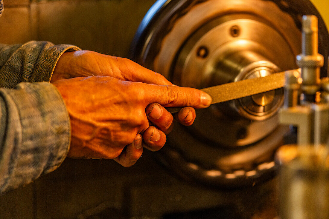 Hands of senior wood and metal craftsman using tools in workshop 