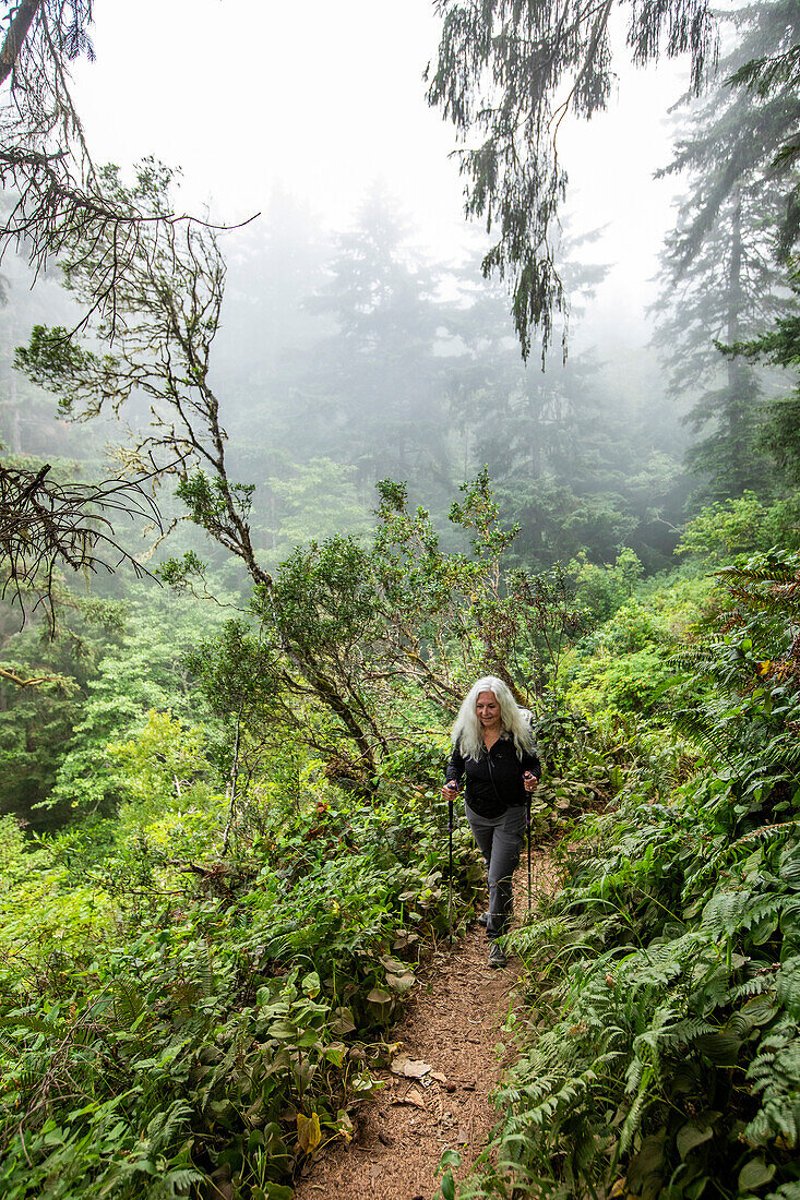 Senior woman hiking on hill with nordic walking poles