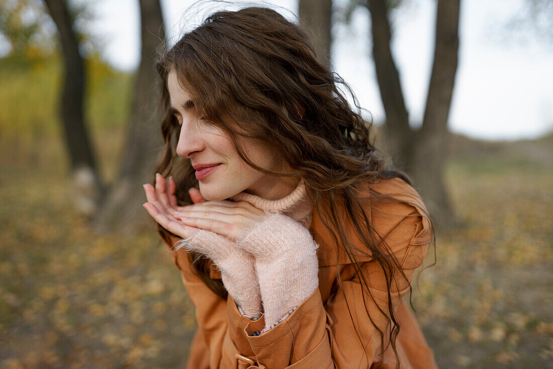 Portrait of smiling woman with hands on chin in forest