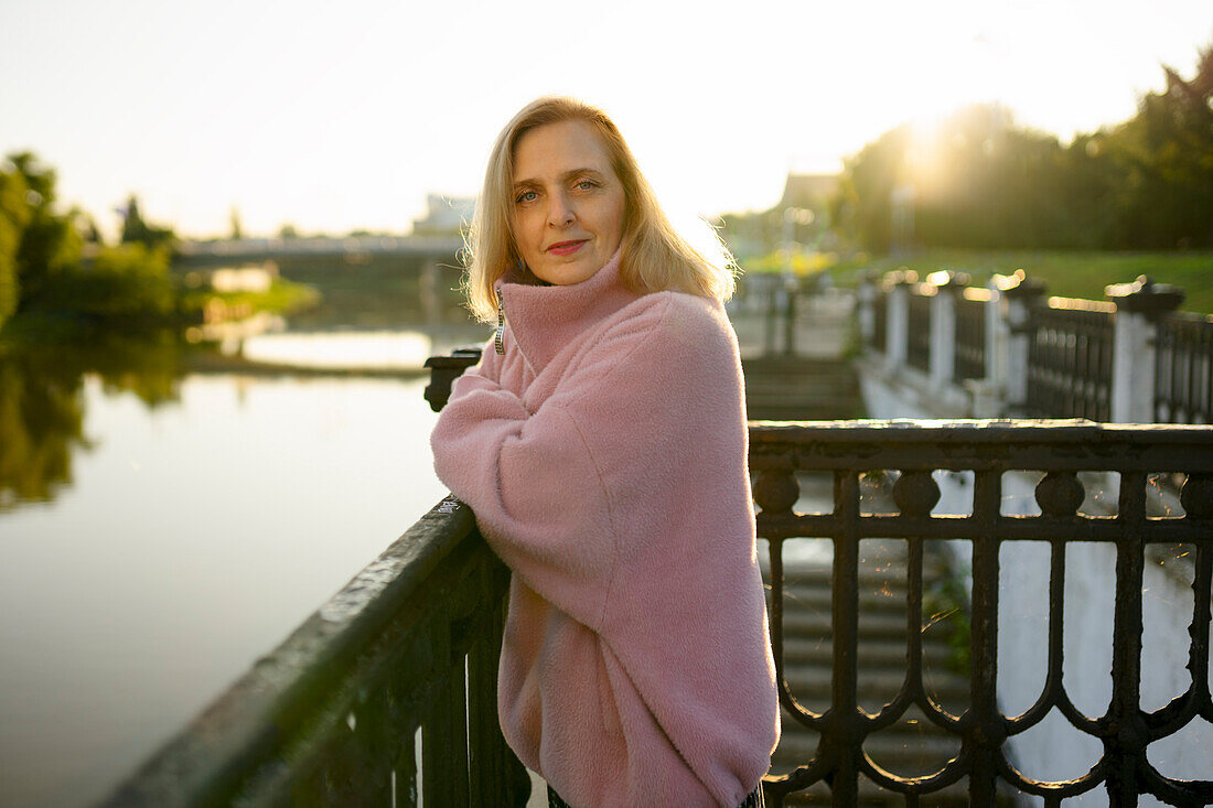 Portrait of mature woman standing by river at sunrise