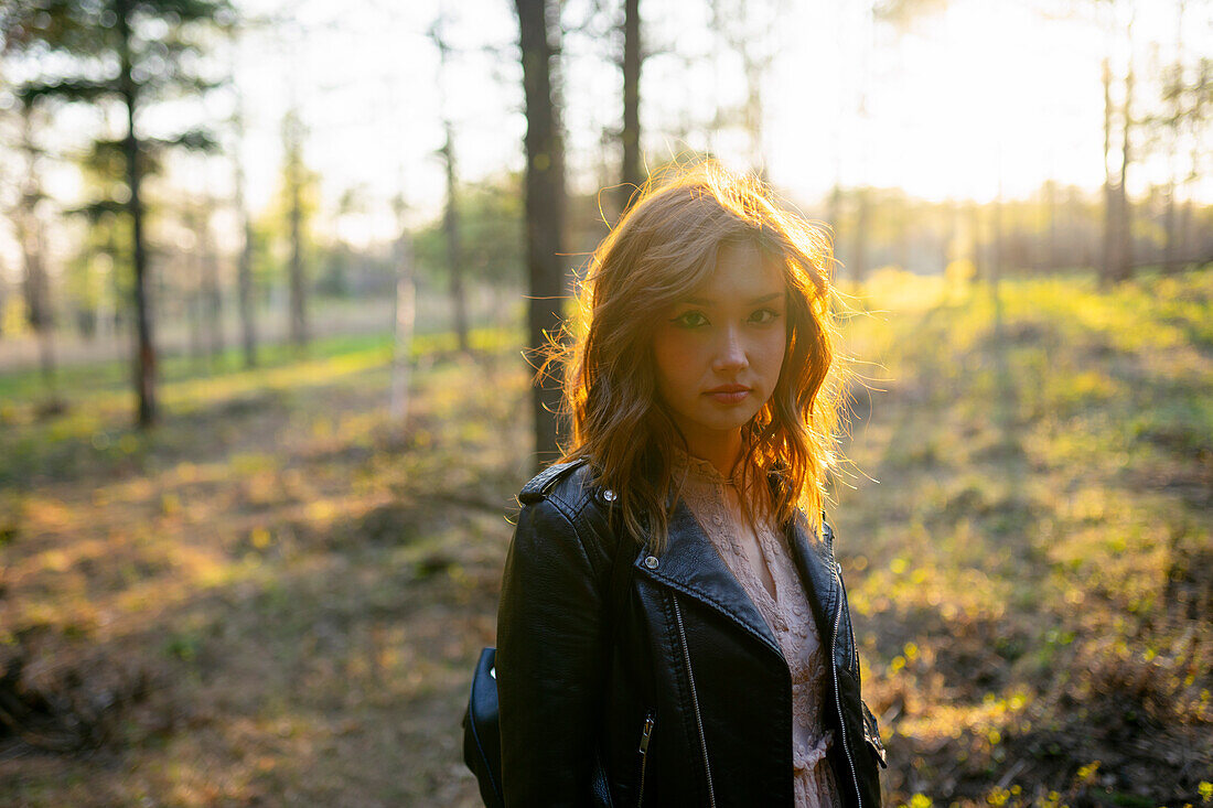 Portrait of woman standing in forest on sunny day