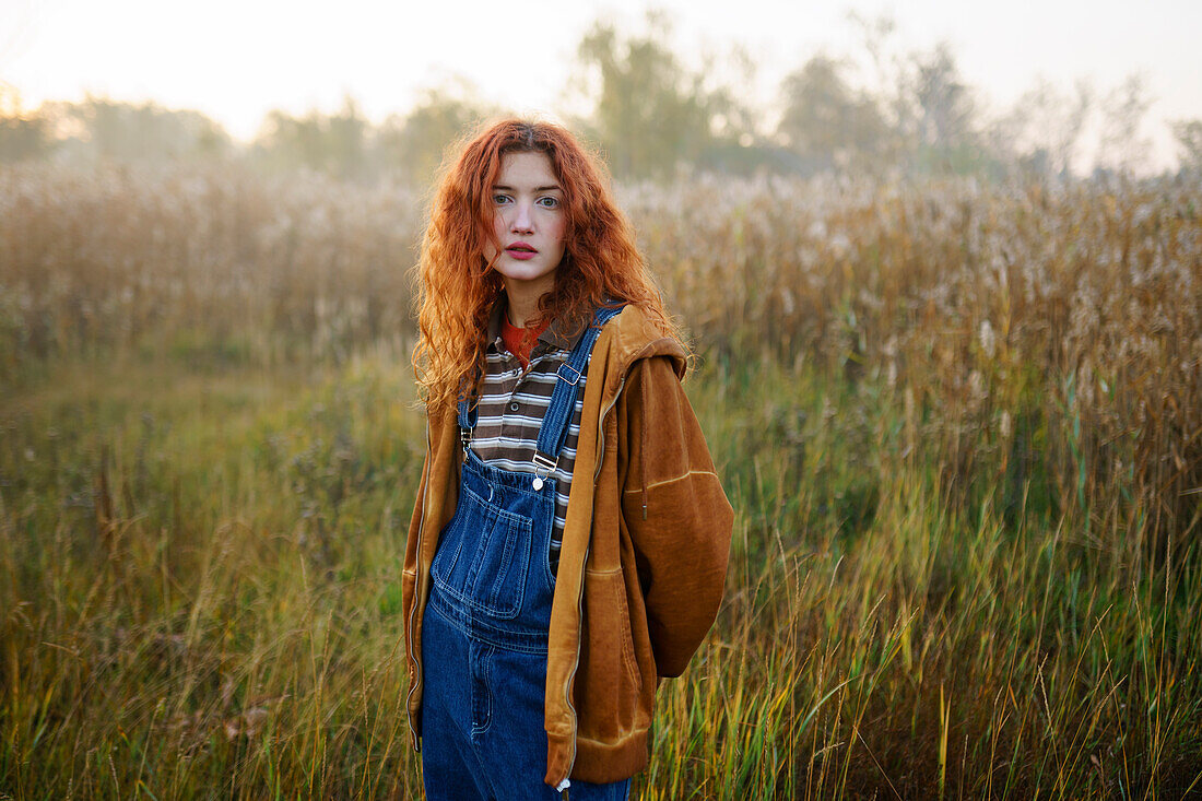 Portrait of young woman standing in field at dawn