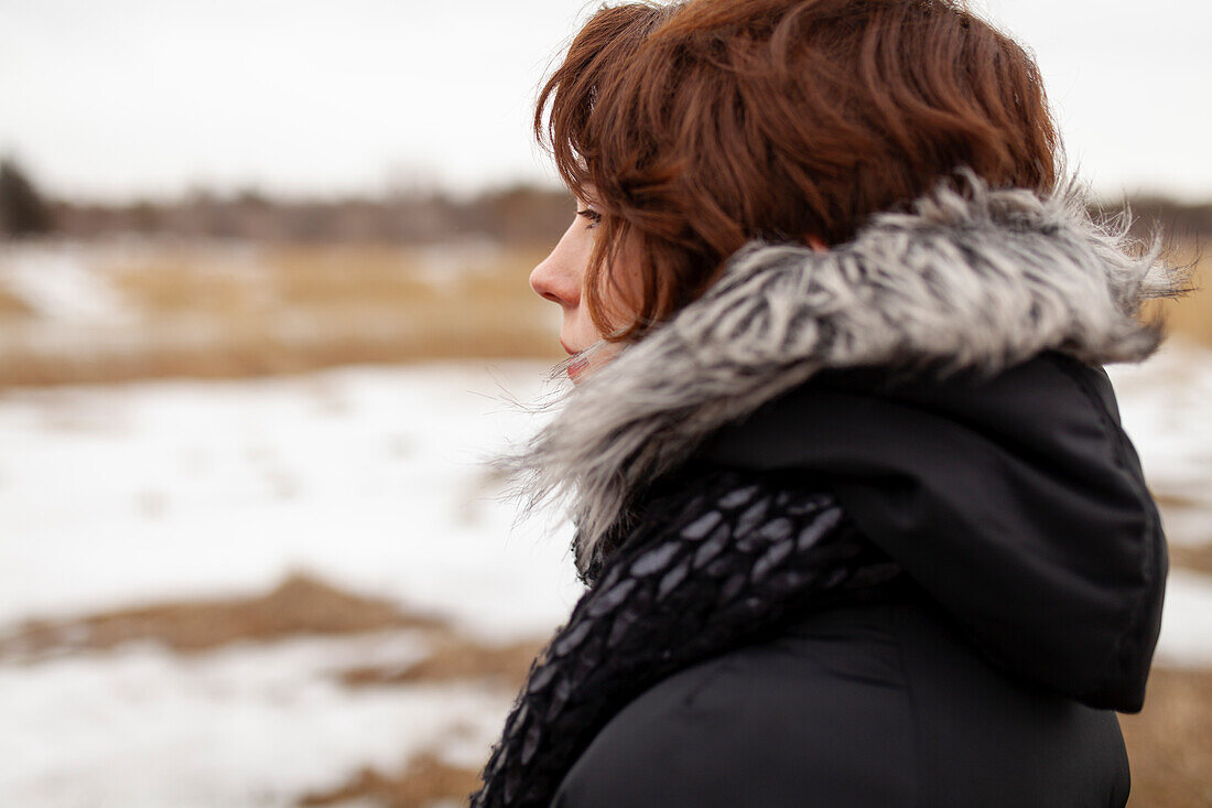 Portrait of thoughtful woman looking at field in winter scenery