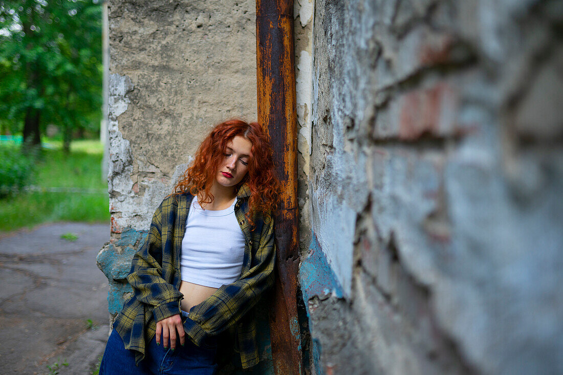 Tired woman with closed eyes leaning on building wall