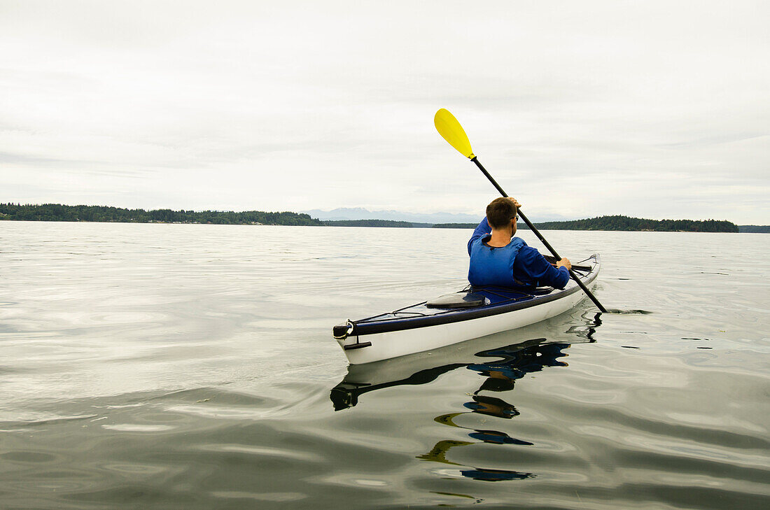 Mann fährt Kajak auf einem See