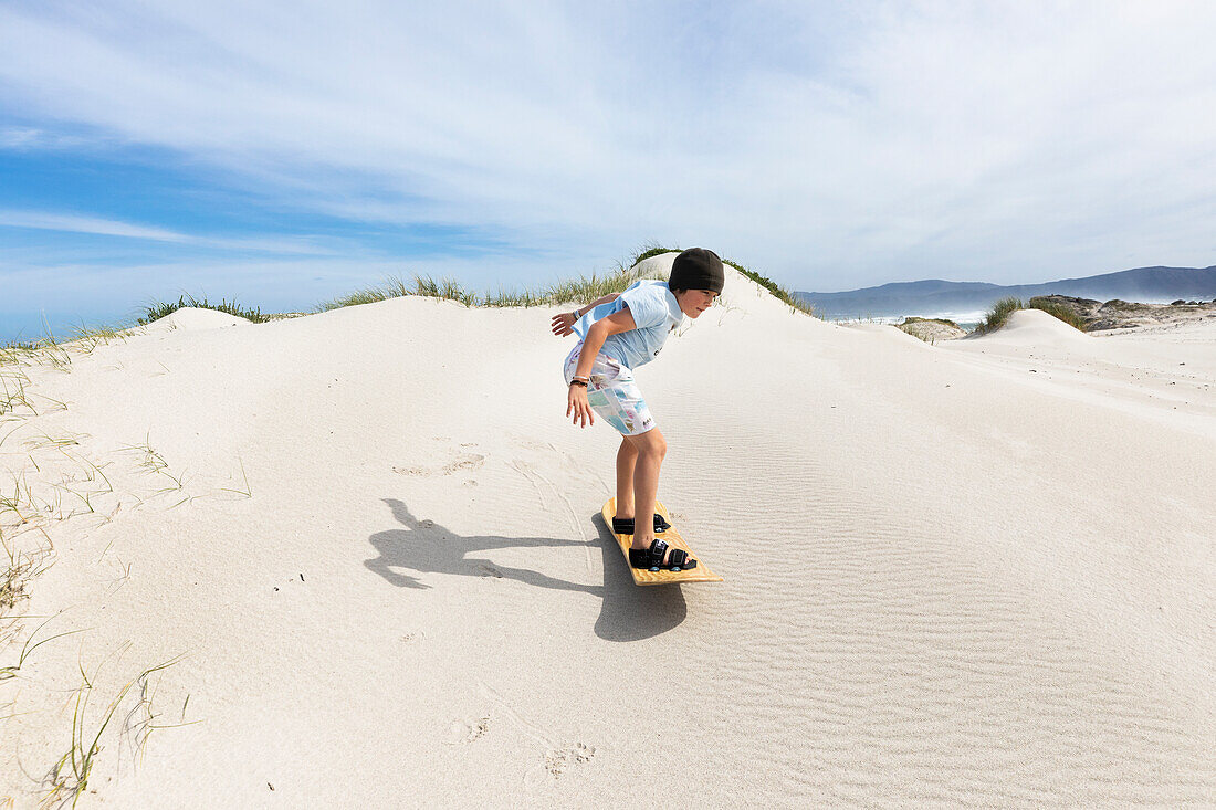 Boy (10-11) sand boarding in Walker Bay Nature Reserve