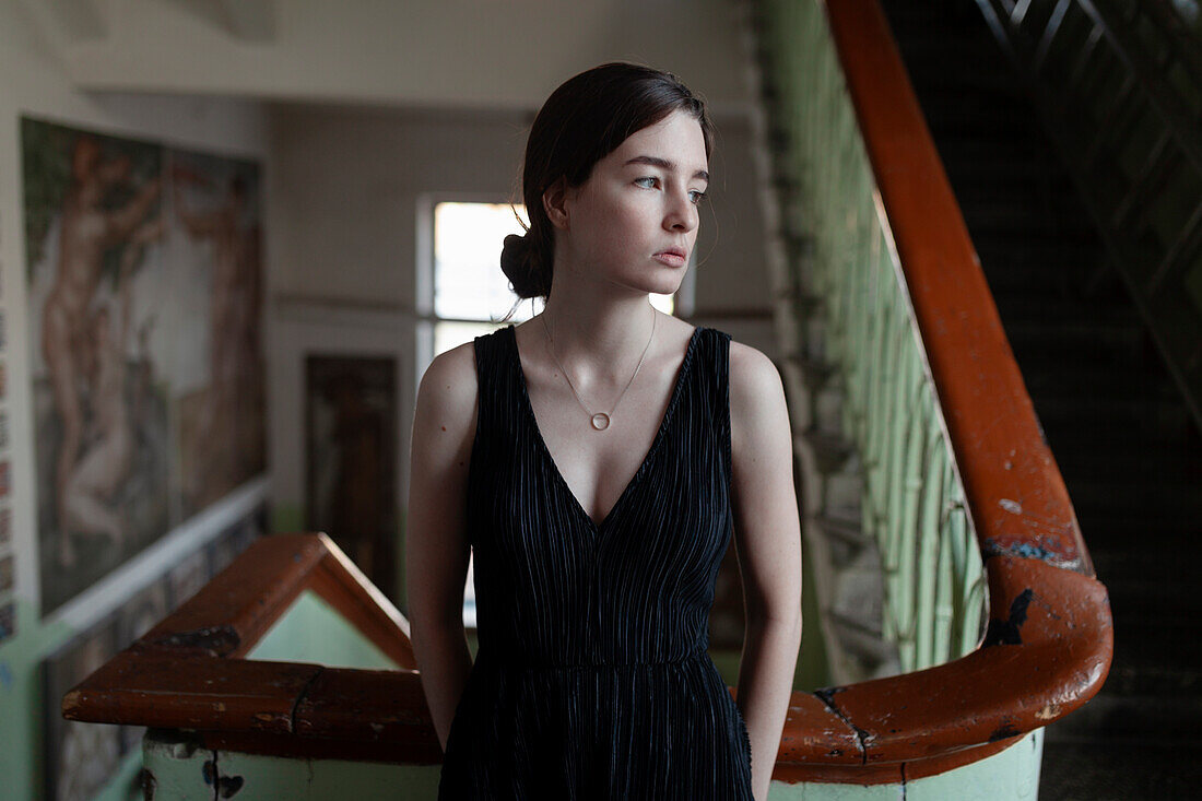 Young sad woman leaning at old railing