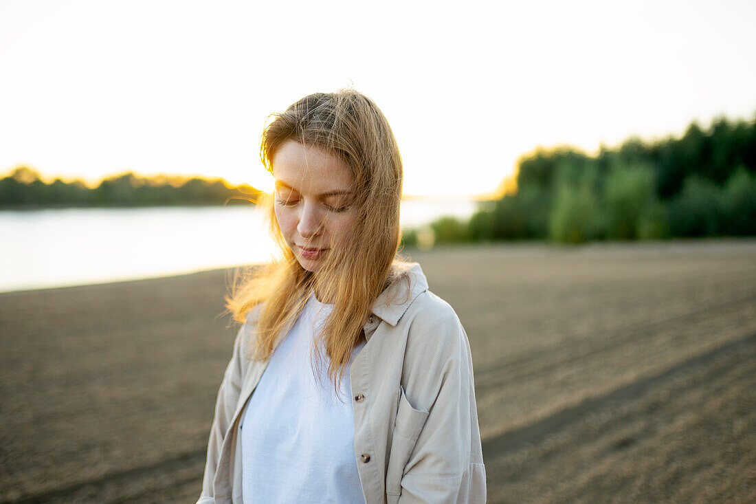 Porträt einer am Strand stehenden Frau bei Sonnenuntergang