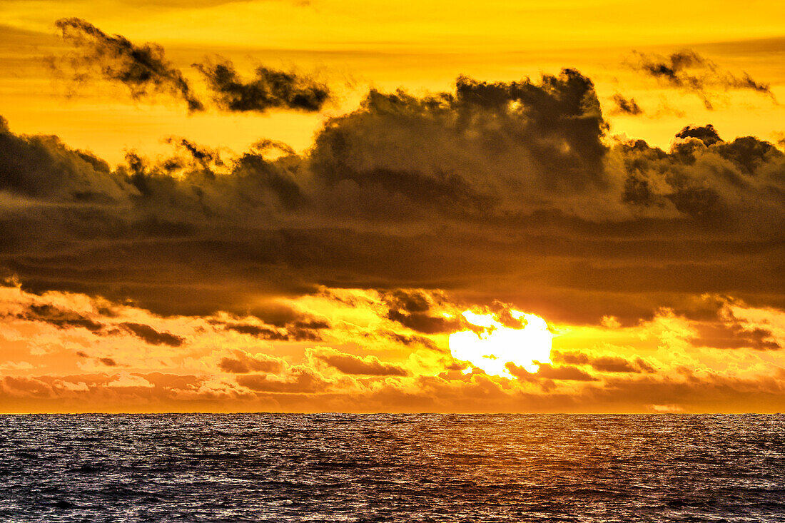 Das karminrote Licht der untergehenden Sonne spiegelt einen roten Schein am Strand von Pererenan Beach, Bali, Indonesien