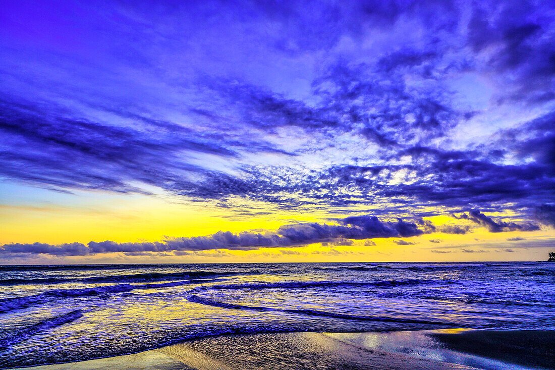 Das goldene Licht der untergehenden Sonne reflektiert einen goldenen Schimmer auf dem Strand von Pererenan Beach, während die Wellen auf Bali, Indonesien, anrollen