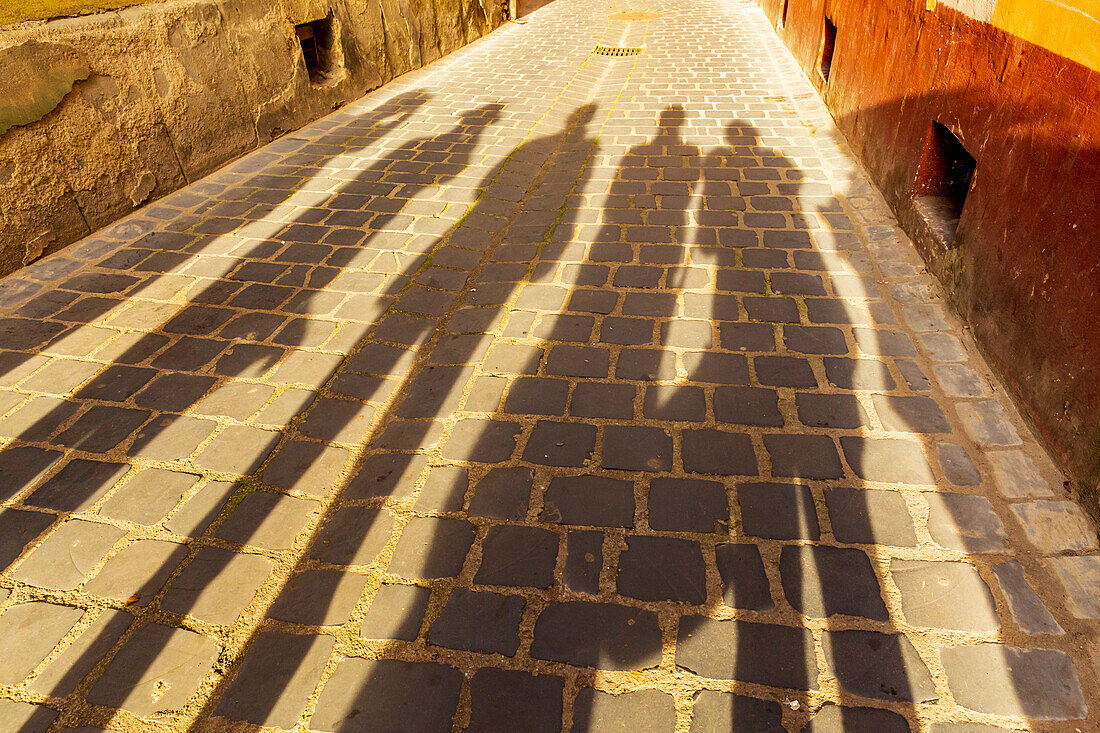 Rumänien, Brasov. Schemenhafte Figuren in Silhouette auf Straßenpflaster.