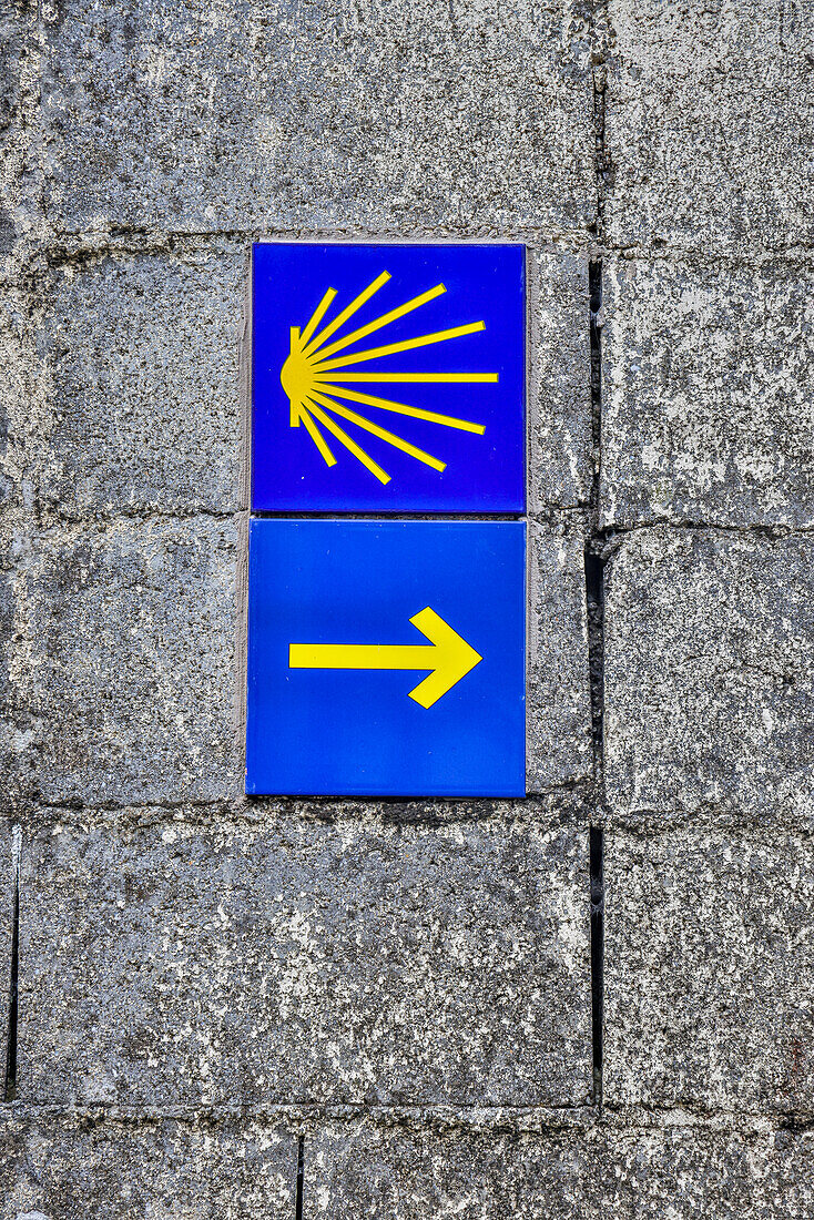 Spain, Galicia. Yellow arrow and clam shell along the Camino de Santiago (Way of St. James) between Lavacolla and Santiago de Compostela