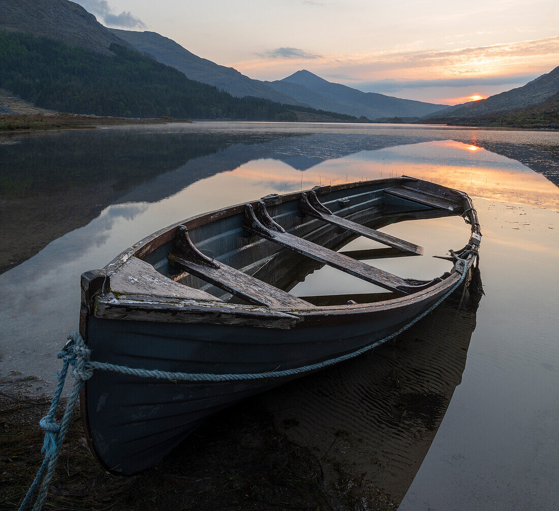 Ireland, Lake Cummeenduff. Partially submerged boat on lake.