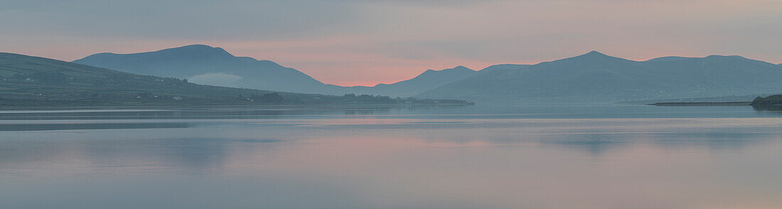 Ireland, Portmagee Bay. Panoramic of sunrise on ocean and mountains.