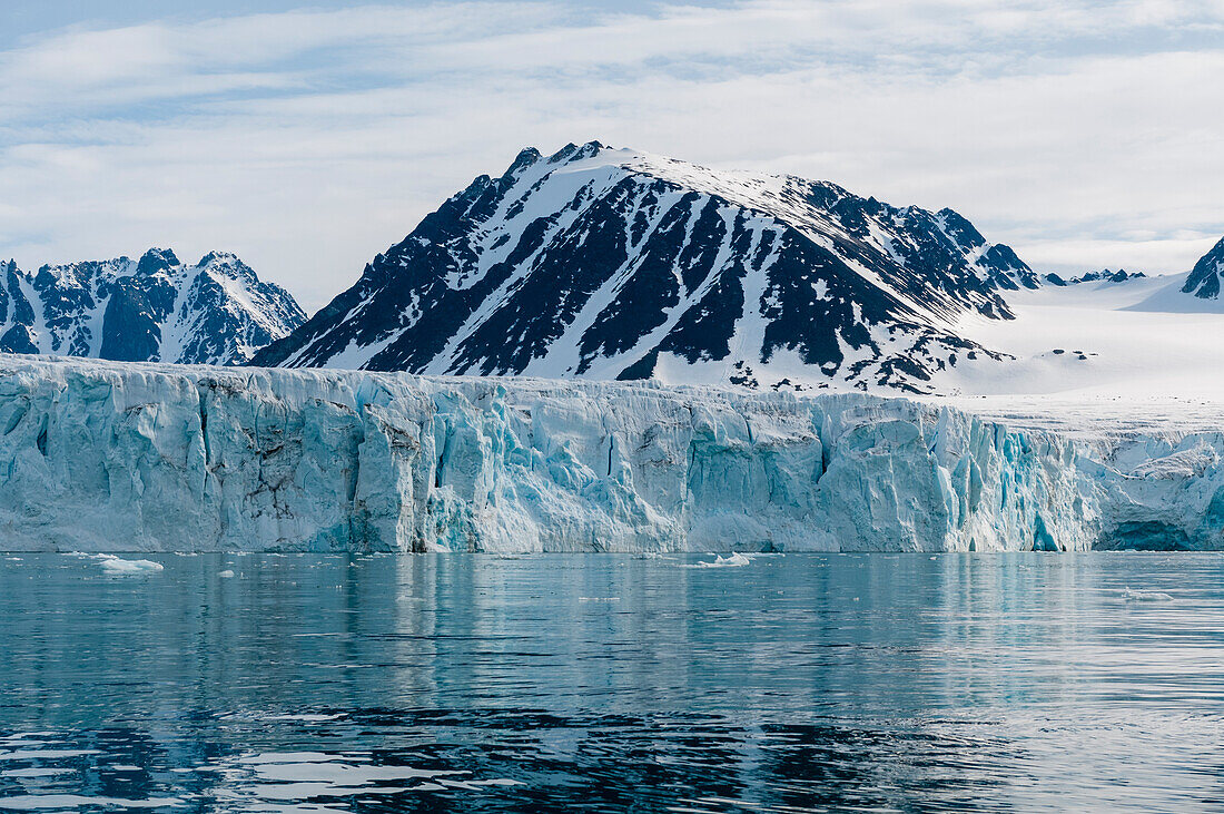 Arctic waters front Lilliehook Glacier and snow streaked mountains beyond. Lilliehookfjorden, Spitsbergen Island, Svalbard, Norway.