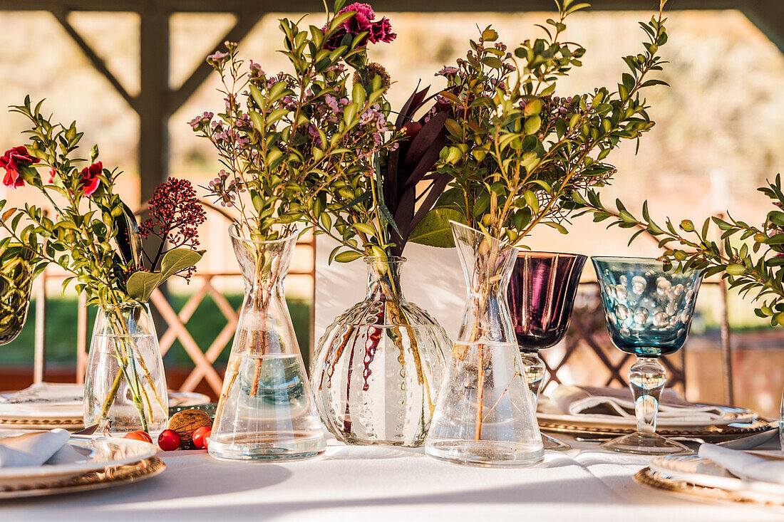 Close-up of transparent glass vases with bunches of fresh flowers placed on table for event