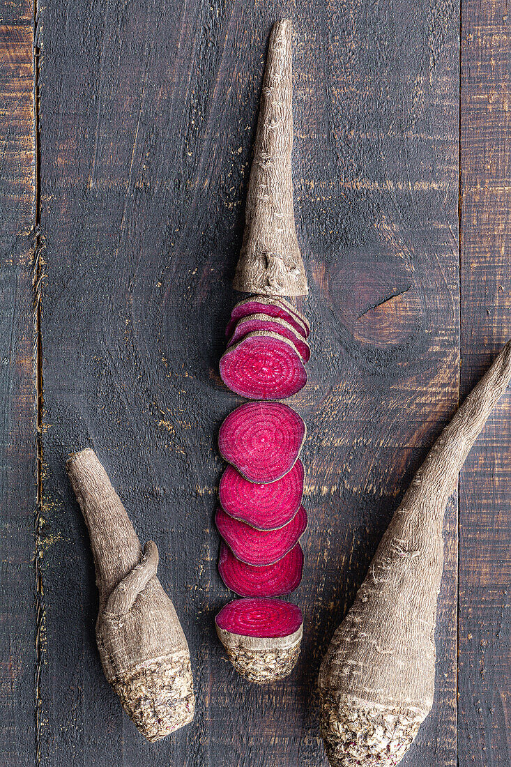 Overhead composition of organic natural beetroot cut into slices and arranged on shabby wooden surface