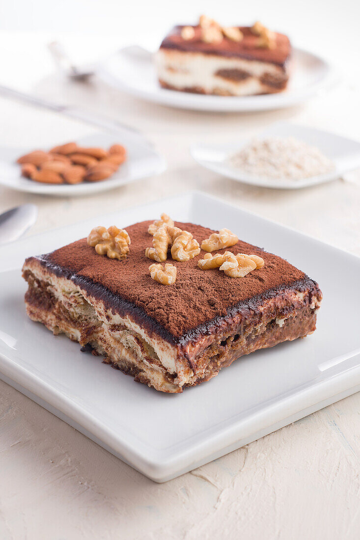 Hoher Blickwinkel auf köstliches Tiramisu-Dessert mit Walnüssen garniert auf einem weißen Tisch