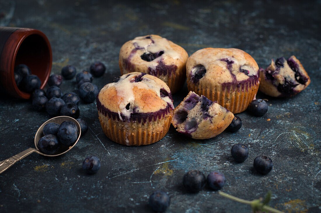 Hohe Winkel von süßen hausgemachten Muffins mit Sahne und Blaubeeren in der Nähe von Löffel Minzblatt und Blume und bereit für Dessert