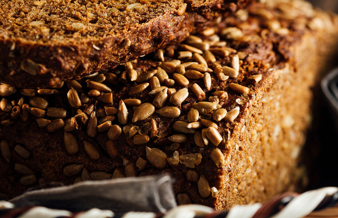 Nahaufnahme von leckerem geschnittenem Brot mit brauner Kruste und knusprigen Sonnenblumenkernen in einem Weidenkorb