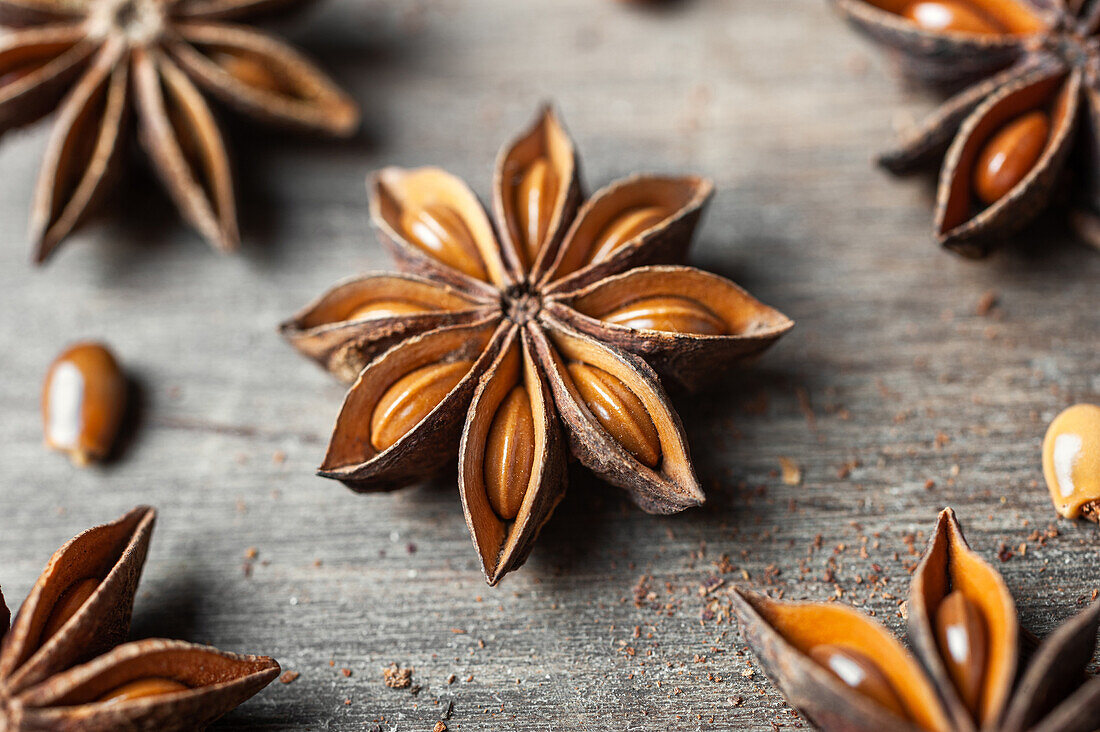 Nahaufnahme von aromatischen getrockneten Anissternen mit verstreuten Samen auf rustikalem Holztisch für Gastronomiekonzept Hintergrund