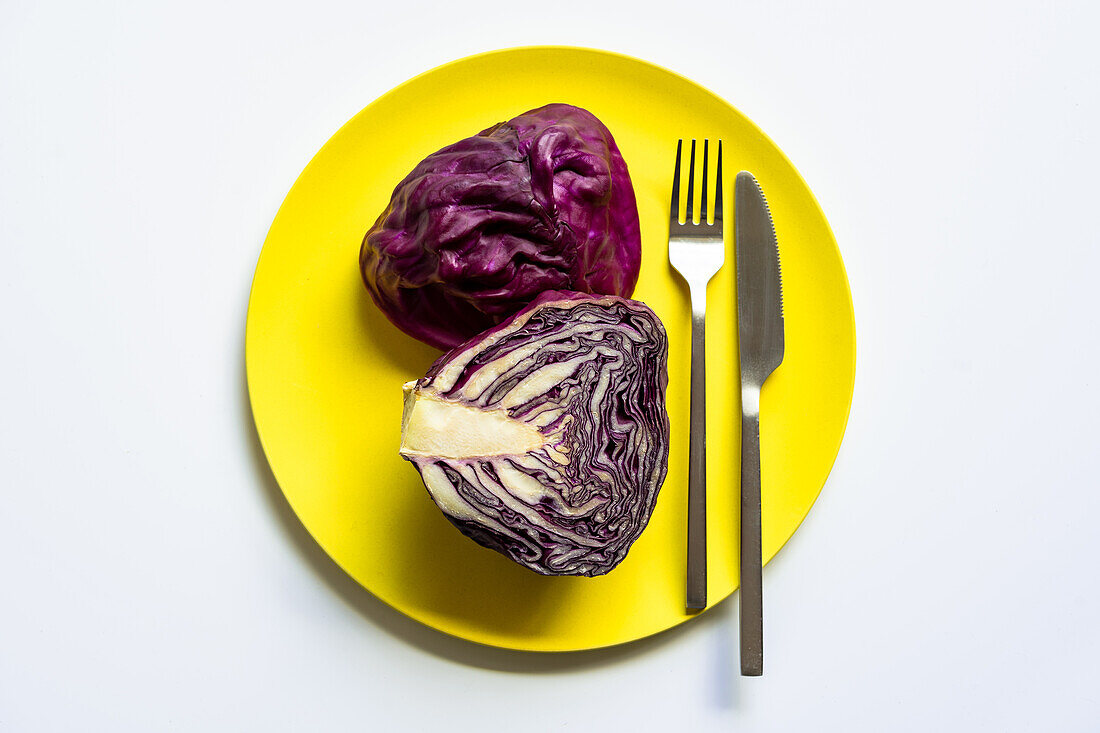 Halbierter Rotkohl von oben auf gelbem Teller auf weißem Hintergrund