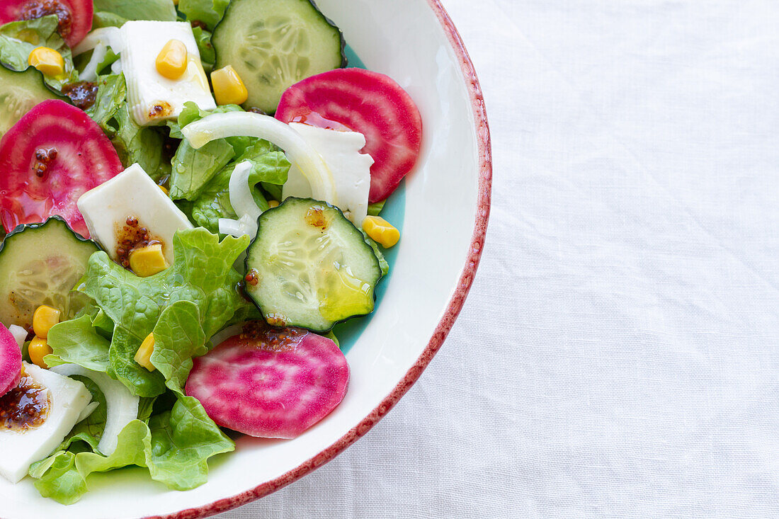 Leckerer vegetarischer Salat mit Gurke und Roter Bete mit grünen Blättern und Eiern mit Mais in einer Schüssel auf dem Tisch