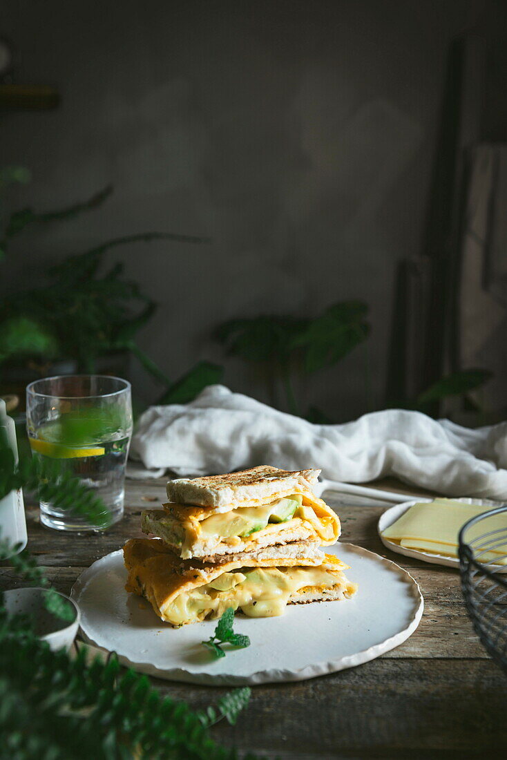 Avocado, Käse, Omelett-Sandwich auf Keramikteller auf Holztisch serviert