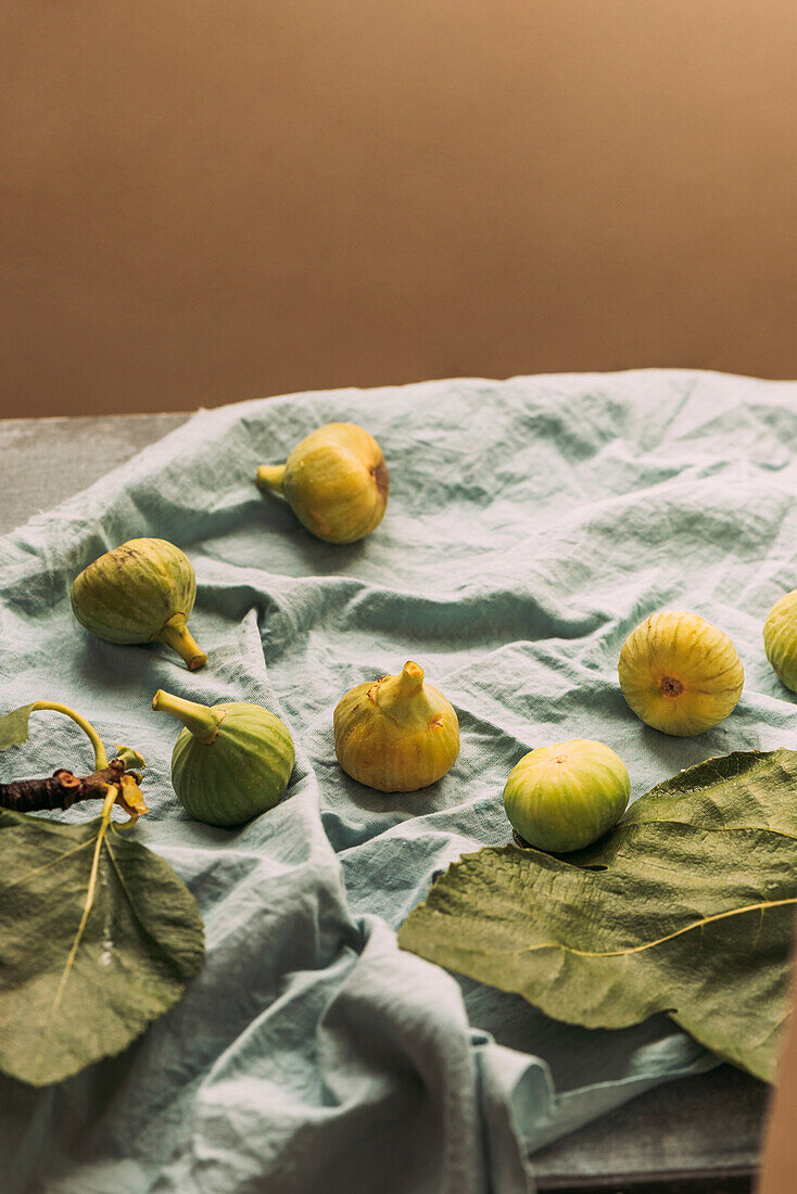 Reife süße grüne Feigen, frisch geerntet von einem heimischen Baum, auf dem pastellblauen Tischtuch. Gesundes und biologisches Obst. Auch bekannt als reife weiße Feigen