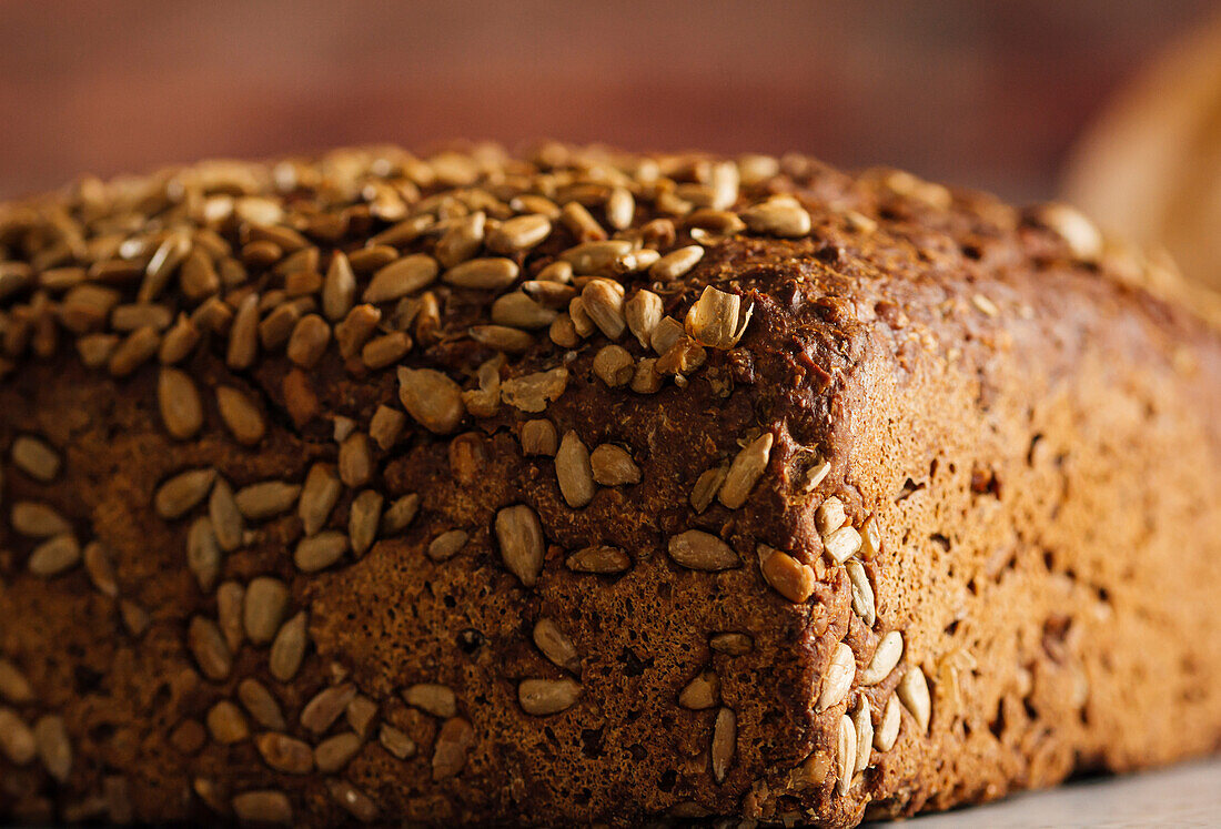 Leckeres Vollkornbrot auf Schneidebrett auf Tisch