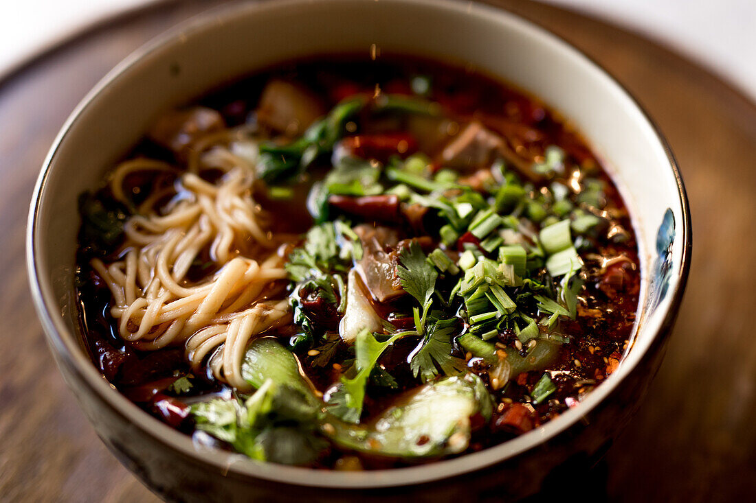 Schüssel mit traditionellen, appetitanregenden, würzigen Ramen auf Holztisch in asiatischem Restaurant