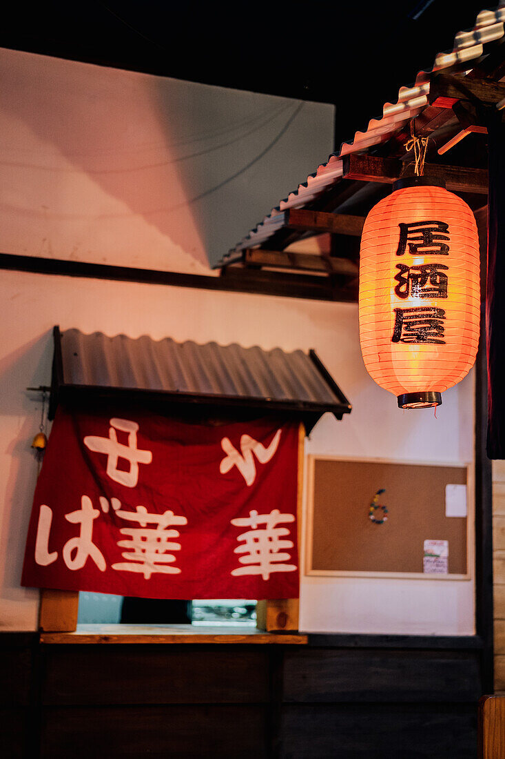 Red cloth with Asian hieroglyphs in window with metal roof of modern building