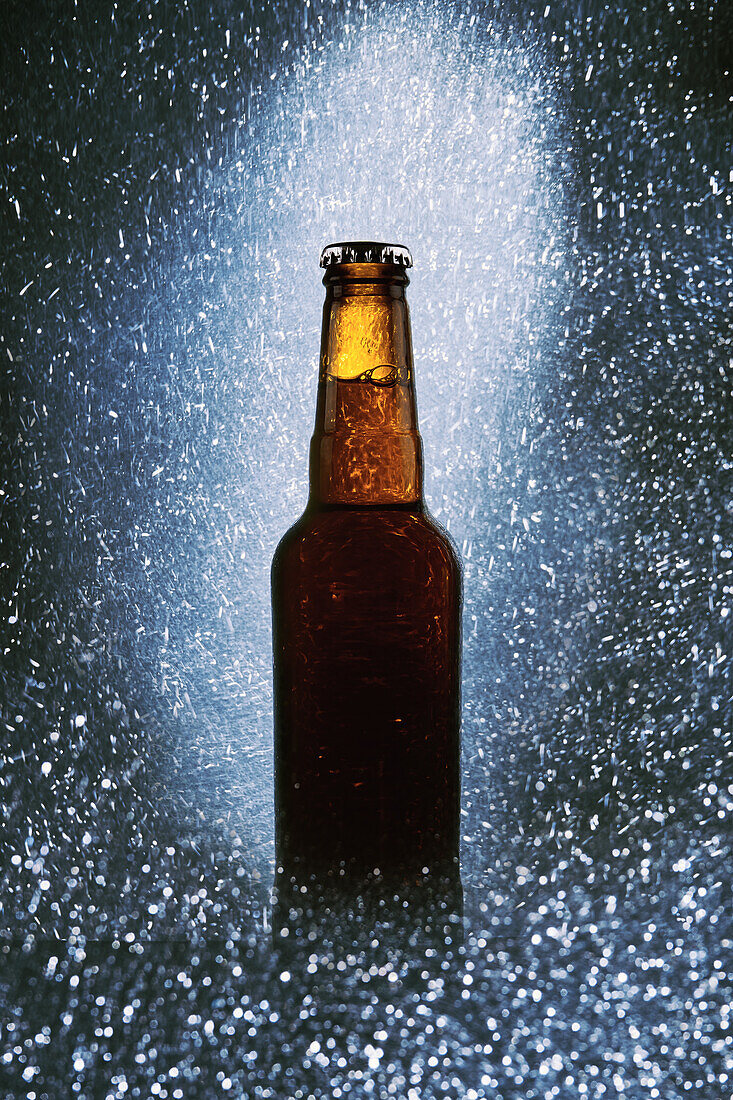 Glass bottle of cold dark beer surrounded by sparkling lights on black background