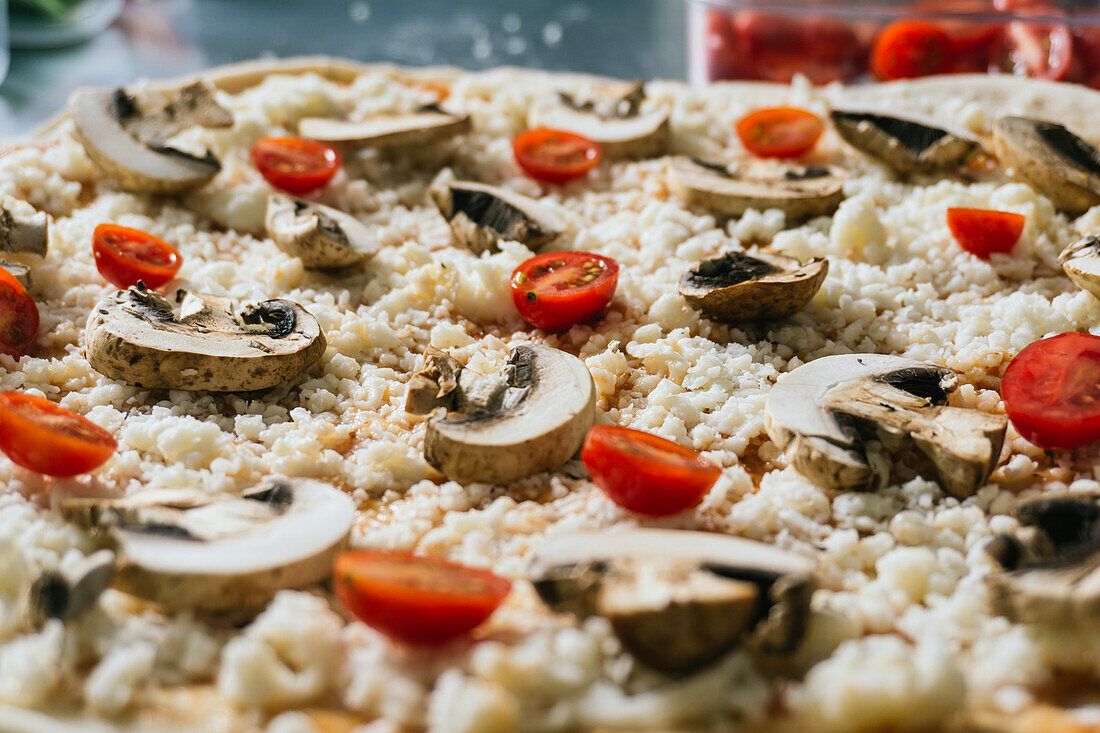 Ungekochte Pizza mit Champignons, Kirschtomaten, Käse und Soße