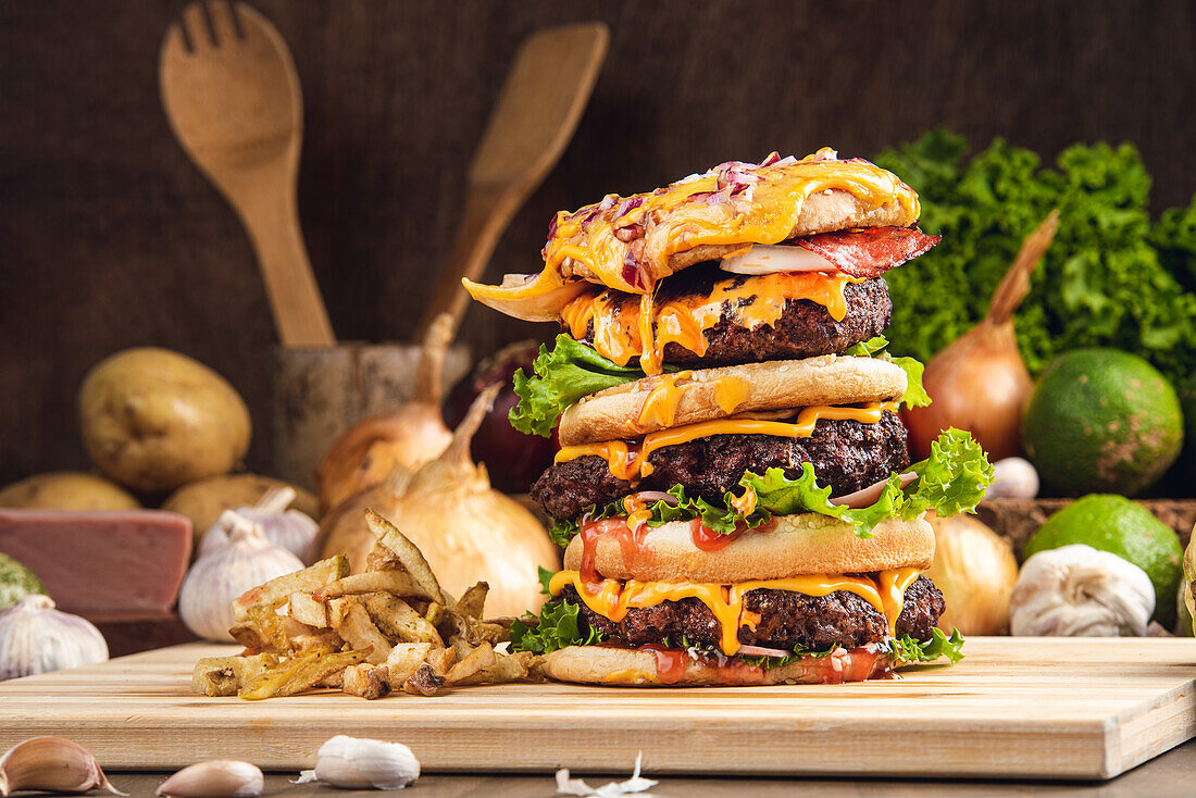 Appetitliche Hamburger mit Gemüse auf Holzbrett mit Pommes frites in Küche