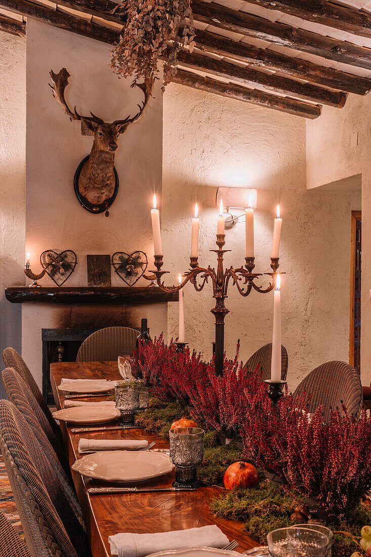 Interieur eines Esszimmers mit Holztisch, Besteck und mit Blumen dekorierten Tellern für das Abendessen