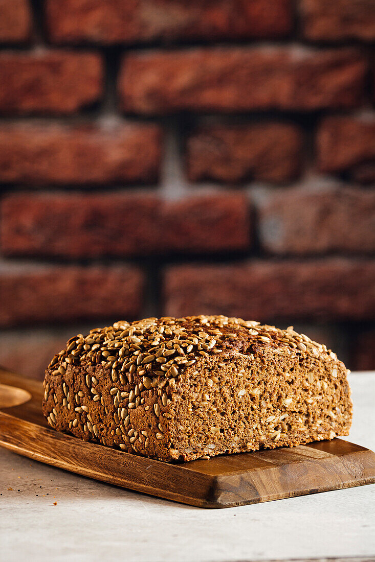 Leckeres Vollkornbrot auf Schneidebrett auf Tisch