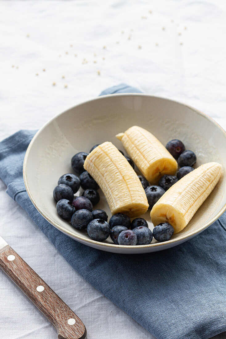 Von oben auf eine runde Schale mit reifen Blaubeeren und geschnittenen Bananen zum Frühstück