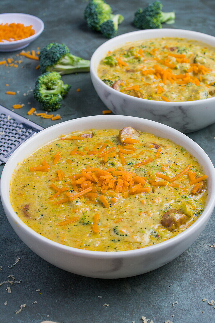 Bowls with delicious soup with broccoli and cheese placed on gray table in restaurant