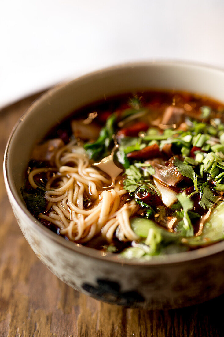 Schüssel mit traditionellen, appetitanregenden, würzigen Ramen auf Holztisch in asiatischem Restaurant