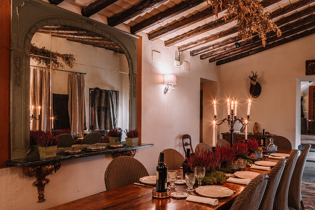 Interieur eines Esszimmers mit Holztisch, Besteck und mit Blumen dekorierten Tellern für das Abendessen