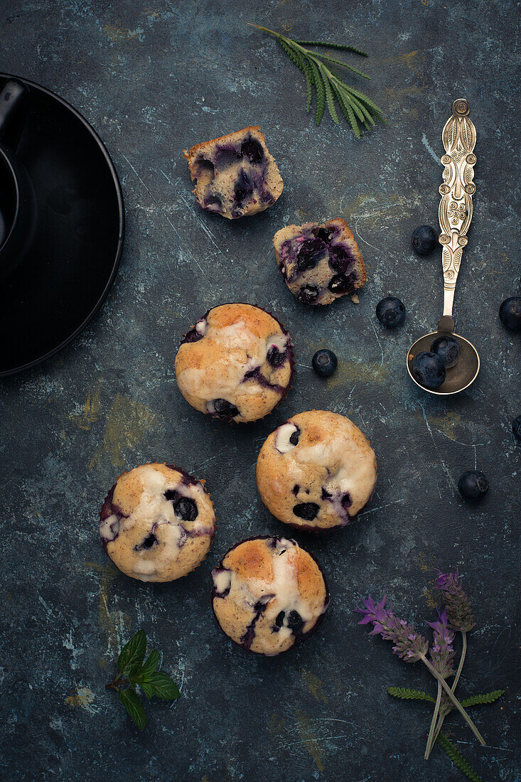 Hohe Winkel von süßen hausgemachten Muffins mit Sahne und Blaubeeren in der Nähe von Löffel Minzblatt und Blume und bereit für Dessert