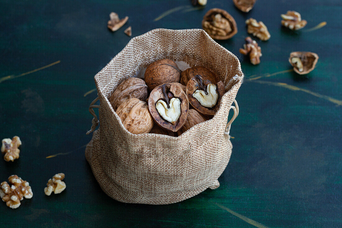 From above bag with whole and halved walnuts with dry nutshells and heart shaped center on table