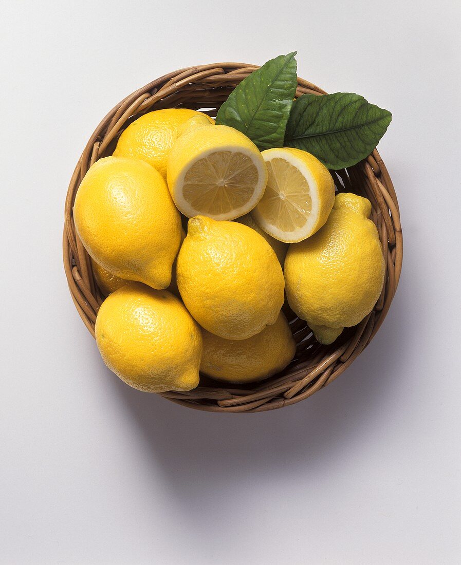 Lemons in basketwork bowl, one halved