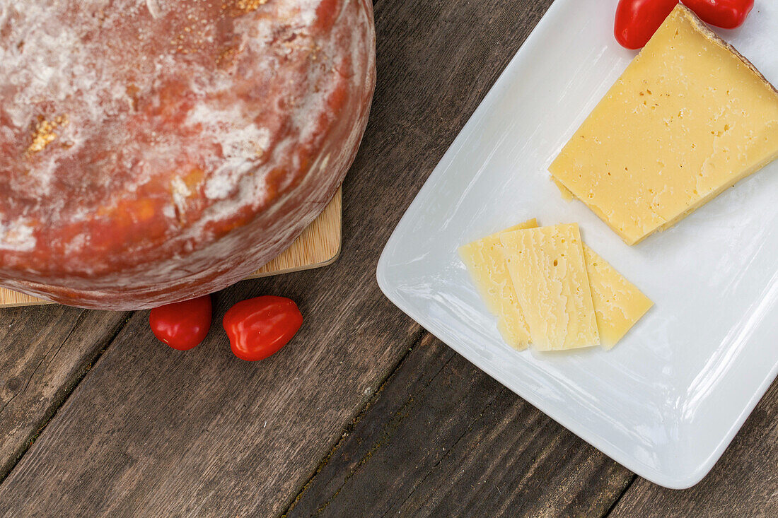 Von oben köstlicher italienischer Pecorino toscano-Käse mit Kirschtomaten auf Schneidebrett auf Holztisch serviert